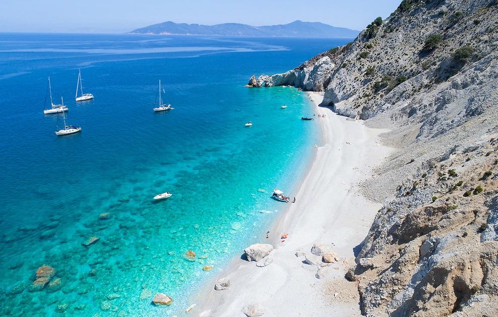 Lalaria beach from above — white marble pebbles, turquoise water and yachts at anchor