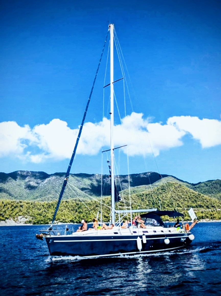 The yacht at anchor along a green coast