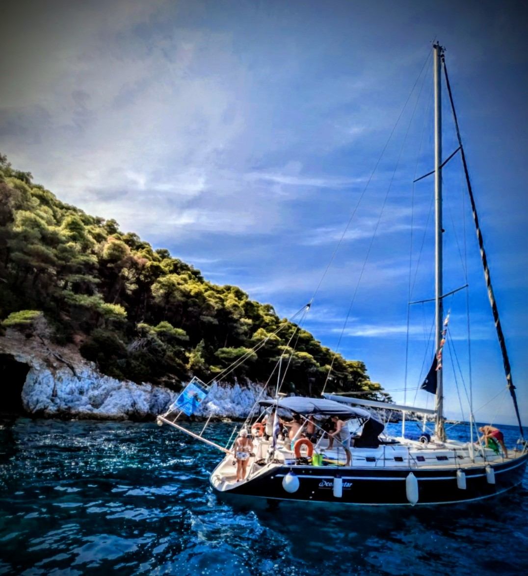 Yacht anchored beneath dramatic cliffs