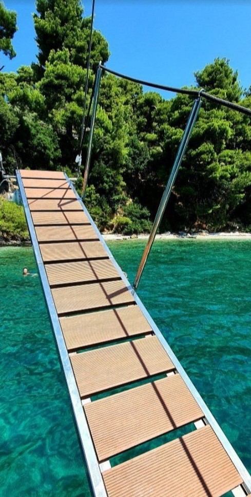 Wooden gangway from the yacht to a pine-fringed beach