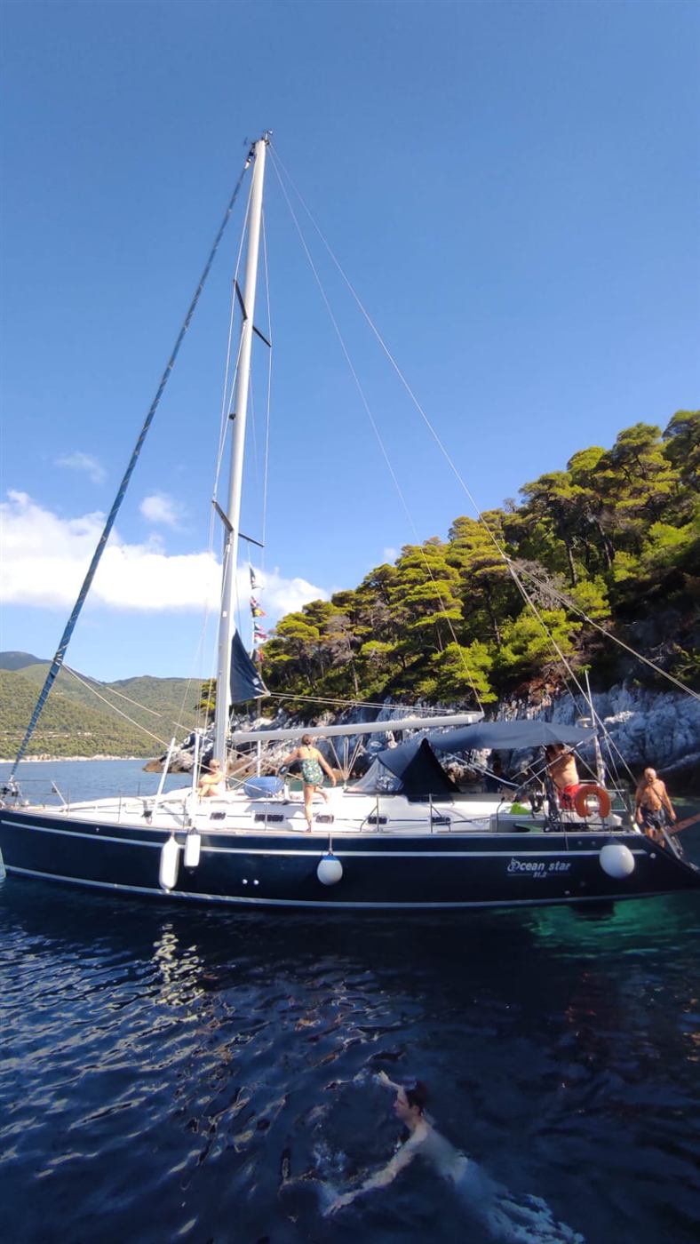 Swimmers around the yacht near a rocky islet